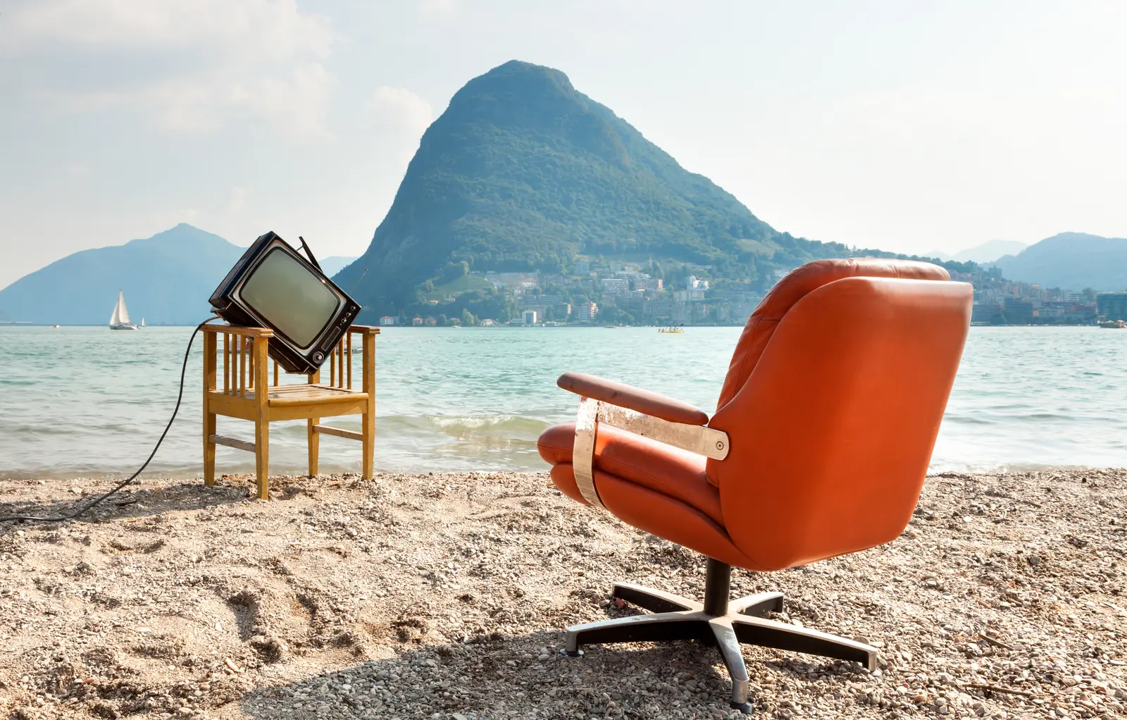 A vintage television on a chair by the water